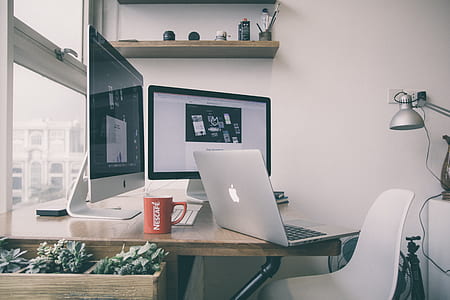 MacBook on desk in front of iMac thumbnail