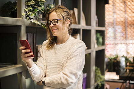 smiling woman using red smartphone near gray layered shelf thumbnail