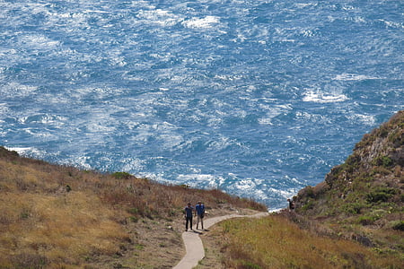 two person walks on road during daytime thumbnail