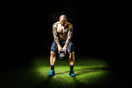 man with tattoos carrying black kettle bell thumbnail