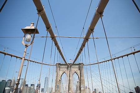 Suspension cables on Brooklyn bridge with American flag waving on the tower thumbnail