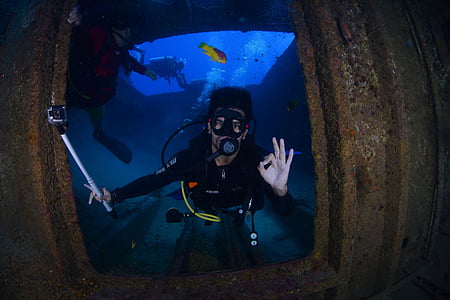 man scuba diving beside metal panel thumbnail