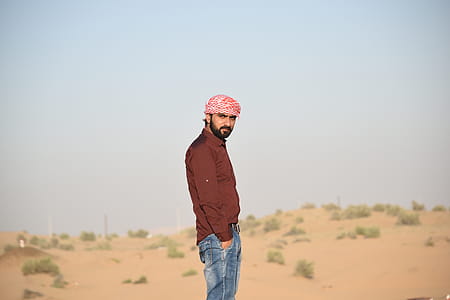 Man in Brown Collared Dress Shirt and Blue Jeans Standing in the Middle of Brown Field thumbnail