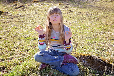 girl doing lotus yoga position in green grass field thumbnail
