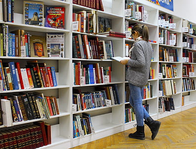 woman reading book near shelves thumbnail