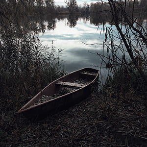 brown canoe beside body of water thumbnail