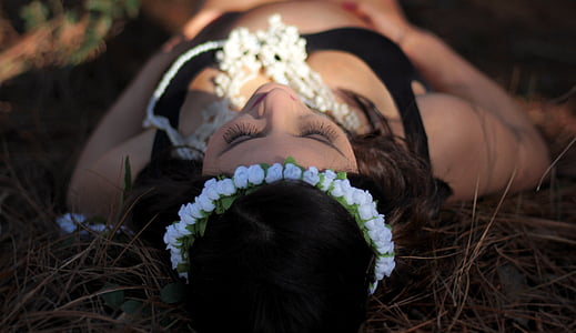 woman lying on grass wearing white flower headdress thumbnail
