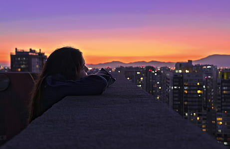 woman resting her head on roof railing during sunset thumbnail