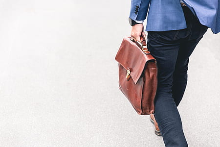 man in blue suit jacket and black pants holding leather bag thumbnail