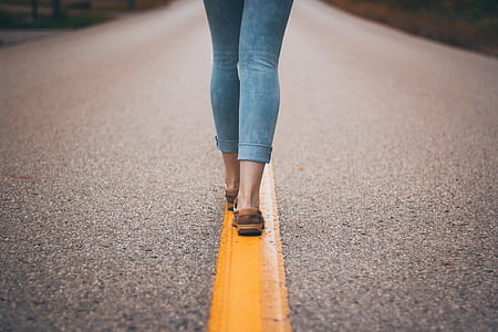 person wearing blue boyfriend jeans walking in the middle of road thumbnail