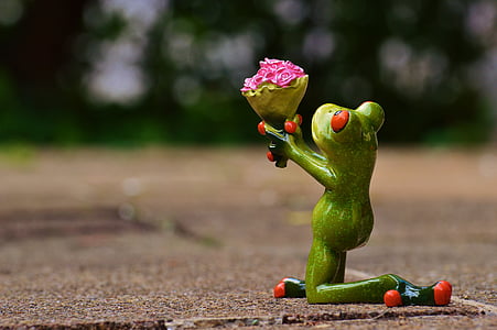 green frog holding bouquet of flowers figurine macro shot thumbnail