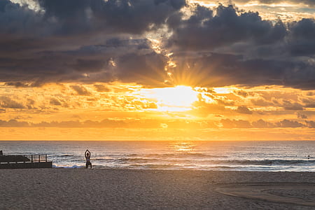person doing yoga exercise on shore during sunset thumbnail