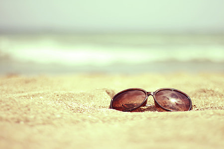 black sunglasses on brown sand thumbnail