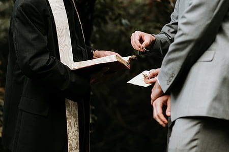 person holding bible standing in front of two men in gray suits thumbnail