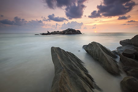 Rock Near a White Foggy Area Under an Orange Sky thumbnail