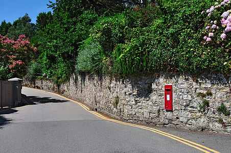 red mail post mounted on wall during daytime thumbnail