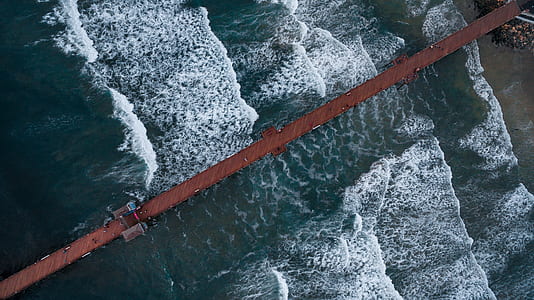 waves of body of water and brown dock during daytime thumbnail