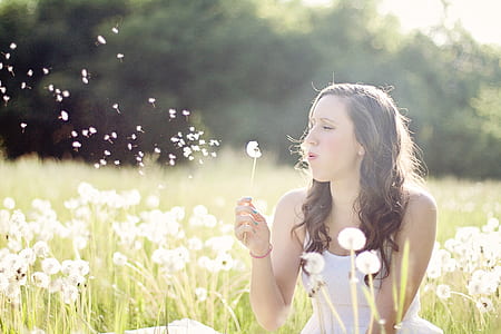 woman wearing white top on dandelion grass field during daytime thumbnail