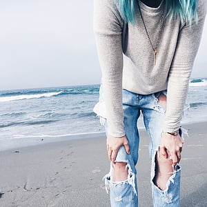 person wearing gray crew-neck long-sleeved shirt and distressed blue denim jeans standing on shore during daytime thumbnail