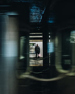 person standing near white wall holding paper bag thumbnail