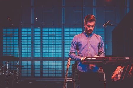 man playing electronic keyboard in dim room thumbnail