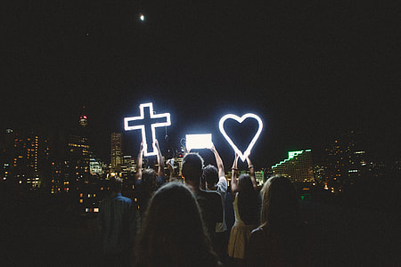 selective focus photography of people holding cross and heart lights thumbnail