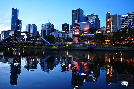 high-rise buildings reflected on calm body of water at dusk thumbnail