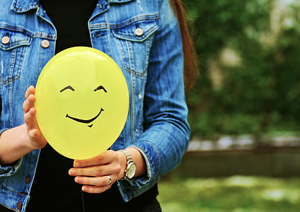 woman in blue denim jacket holding yellow plastic balloon thumbnail