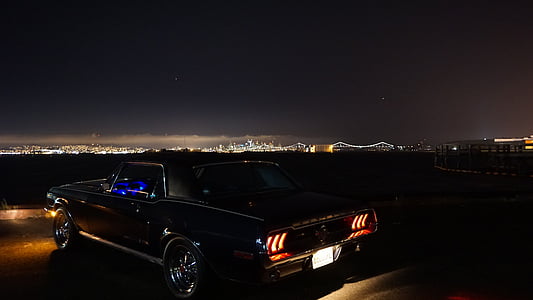 black coupe parked on open field at night thumbnail
