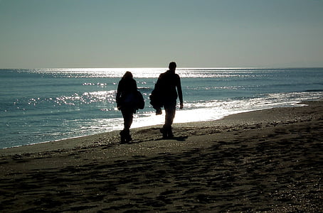 man and woman walking on seashore at daytime thumbnail