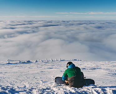 man sitting on snow field during daytime thumbnail