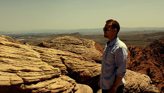 man standing in front of brown rock thumbnail