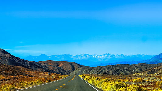 empty highway surrounded with grass and mountain fields thumbnail