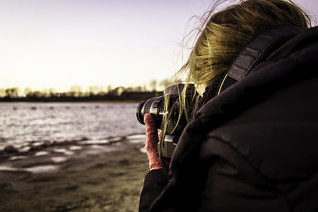 woman taking photo over body of water during daytime thumbnail