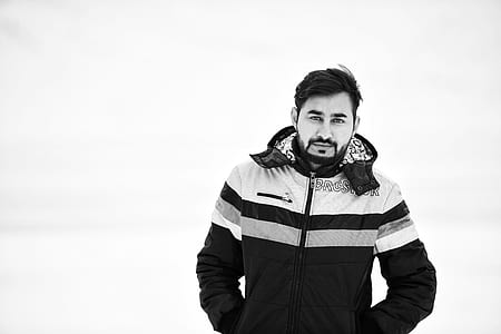 Grayscale Photo of Man Wearing Full-zipped Jacket While Putting His Both Hands Inside Pocket thumbnail