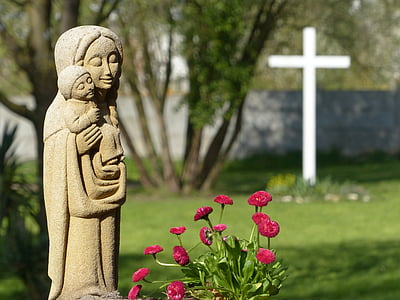photo of mother and child statue standing beside red flowers thumbnail