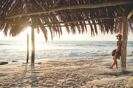 man leaning on hut post looking at beach thumbnail