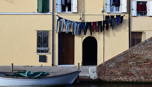 assorted-color clothes hang on wire near yellow wall thumbnail