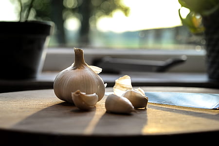 close u p photograph of garlic on brown chopping board thumbnail
