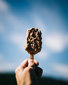 person holding popsicle selective focus photography thumbnail