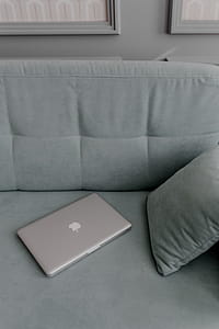 MacBook laptop lying on mint couch thumbnail