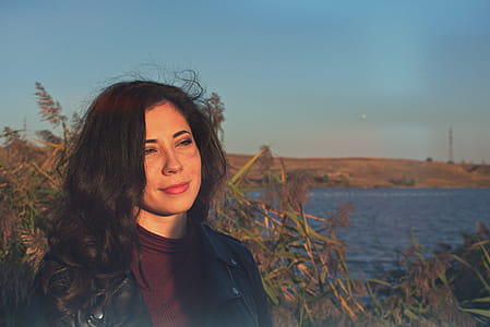 Woman Standing on Grass Near Body of Water thumbnail