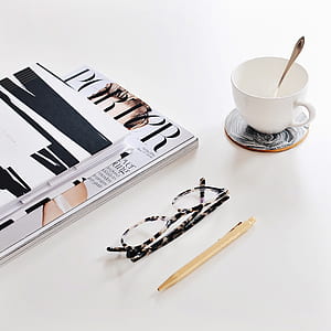 black and white framed eyeglasses near mug and books thumbnail