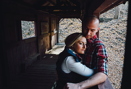 woman hugging man while leaning on brown wall thumbnail