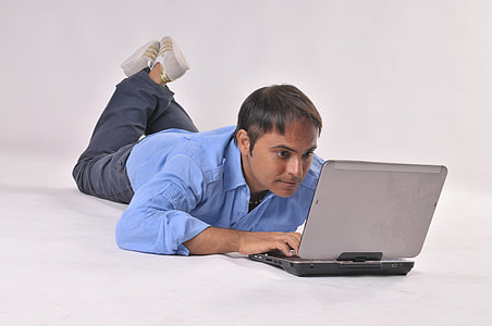 man using laptop computer while laying on ground thumbnail