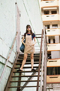 woman in brown dungaree standing on stair thumbnail