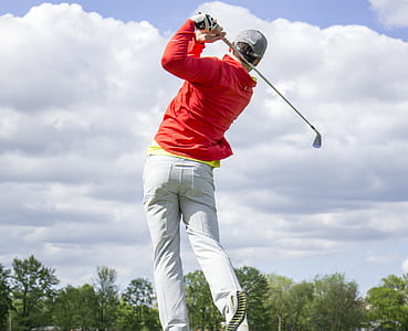 man wearing red dress shirt and gray pants holding gray golf club thumbnail