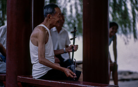 man holding string instrument sitting on brown surface thumbnail