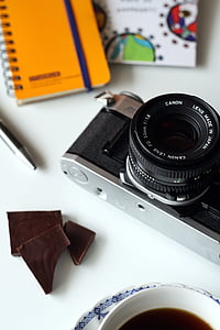 black and gray camera beside notebook on white table thumbnail