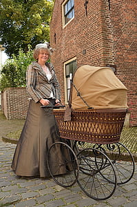 woman wearing Victorian dress while pushing pram stroller thumbnail